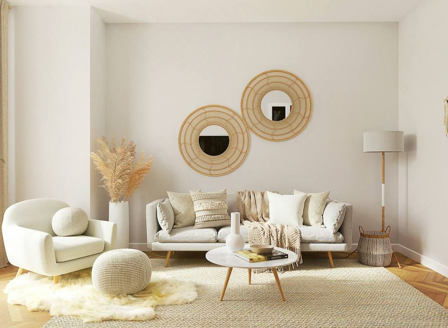 A soft neutral living room with woven accents, cream seating and round rattan mirrors