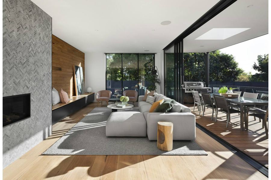 An open living and dining room with wide glass doors leading out to a covered terrace